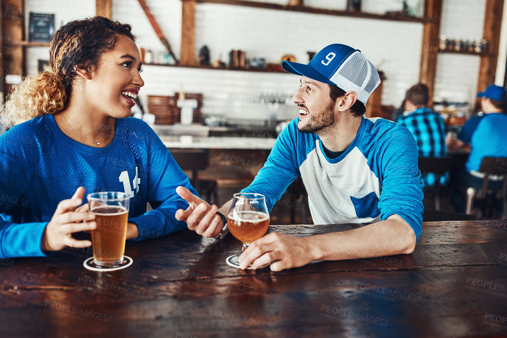 Buy stock photo Sports, talking or couple in pub with alcohol, love or social celebration of competition together. Relax, soccer game or people in bar for watch party, beer drinks or fans at diner for happy hour