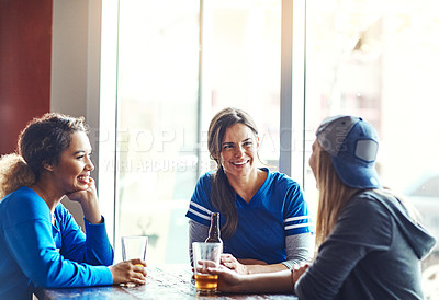Buy stock photo Cropped shot of three young women having beers in a bar