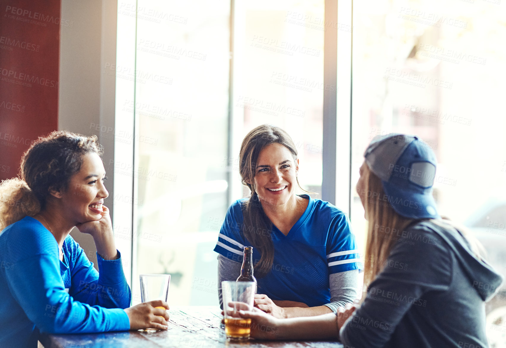 Buy stock photo Cropped shot of three young women having beers in a bar