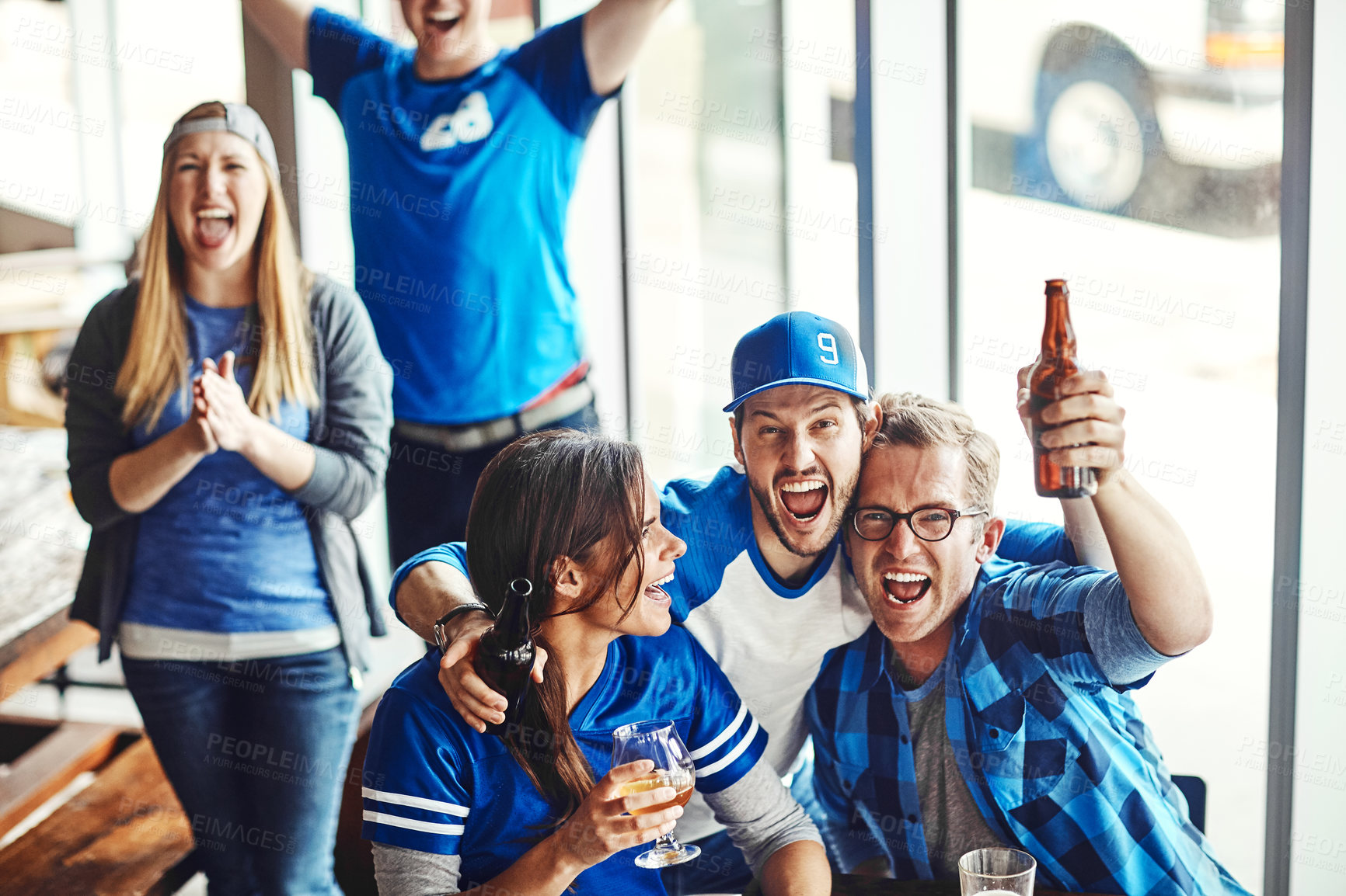 Buy stock photo A group of excited friends cheering on their favourite team at the bar