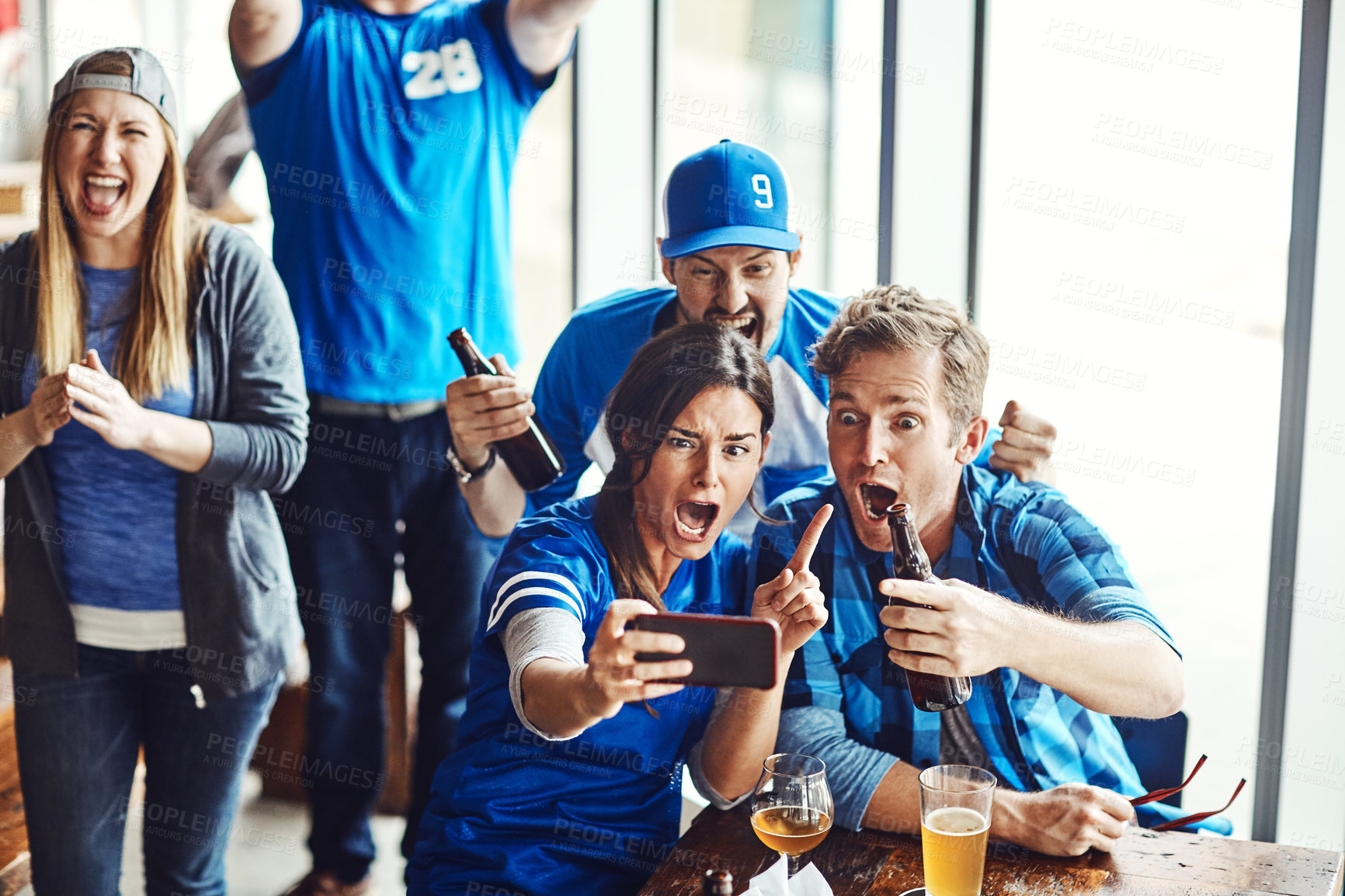 Buy stock photo A group of excited friends cheering on their favourite team at the bar