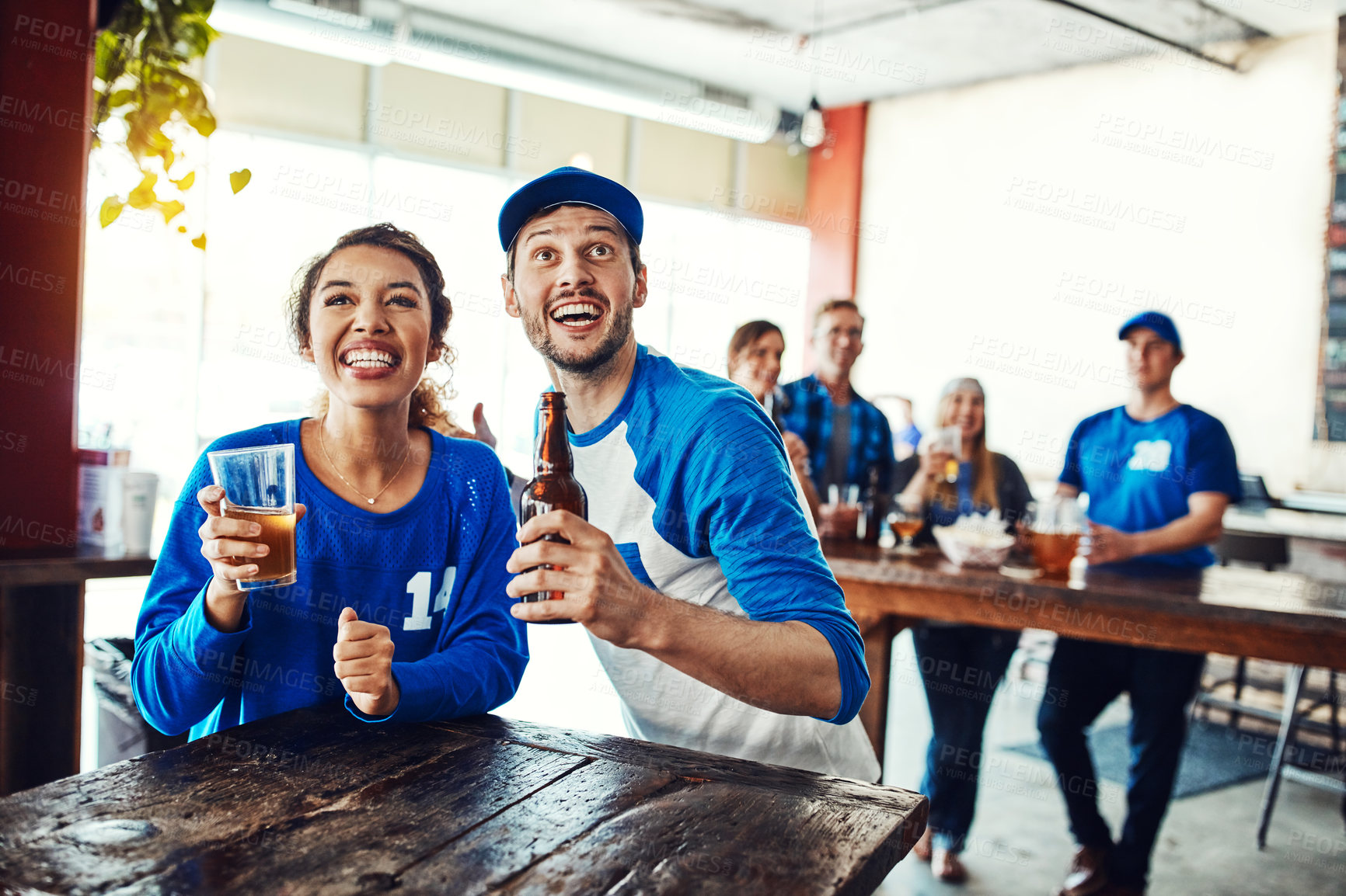 Buy stock photo Shot of a young couple having beer while watching the game in a bar