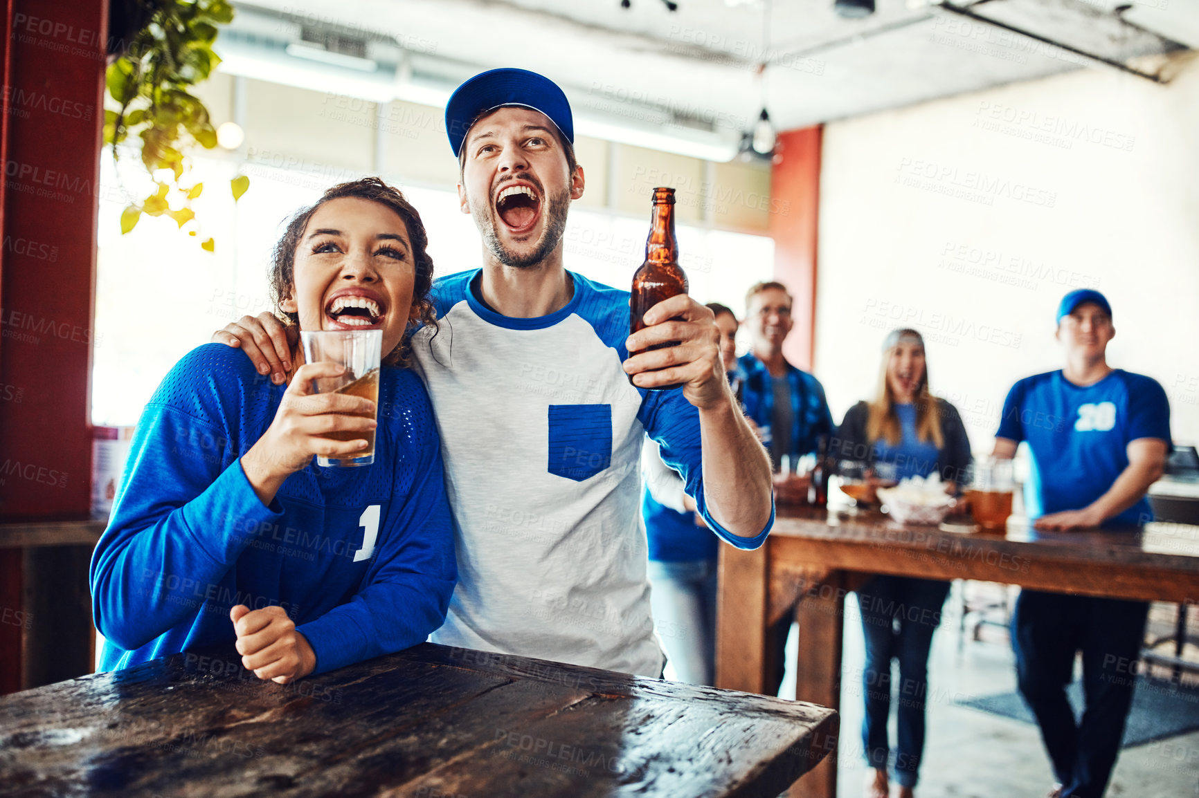 Buy stock photo Shot of a young couple having beer while watching the game in a bar