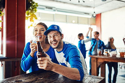 Buy stock photo Shot of a young couple having beer while watching the game in a bar
