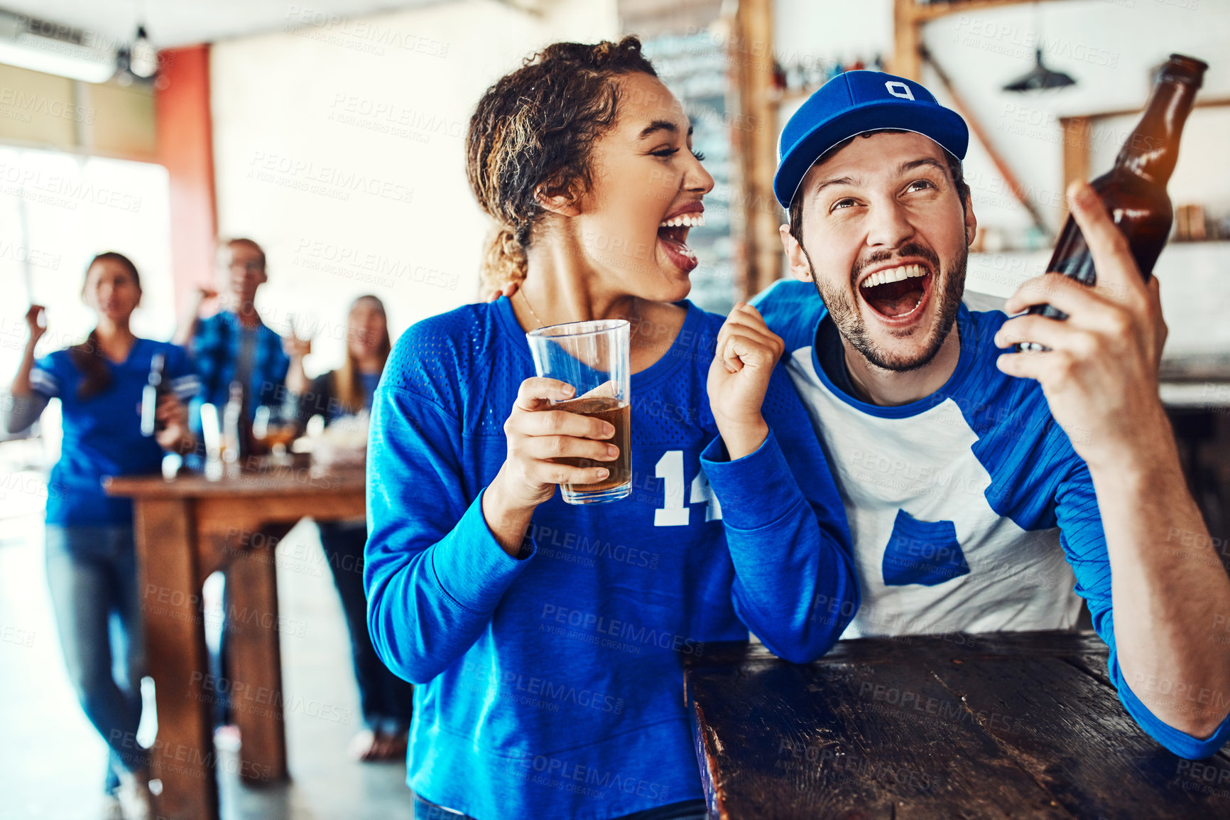 Buy stock photo Shot of a young couple having beer while watching the game in a bar