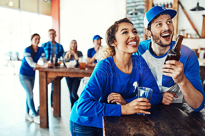 Buy stock photo Shot of a young couple having beer while watching the game in a bar