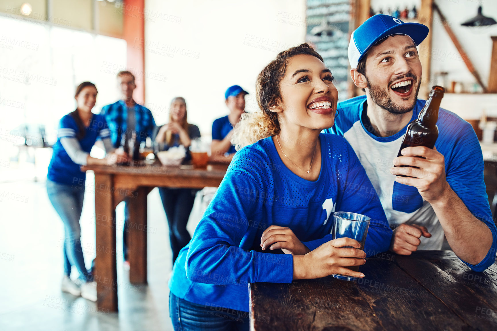 Buy stock photo Shot of a young couple having beer while watching the game in a bar