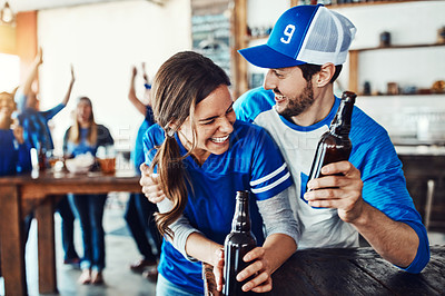 Buy stock photo Shot of a young couple having beer while watching the game in a bar