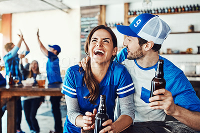 Buy stock photo Shot of a young couple having beer while watching the game in a bar