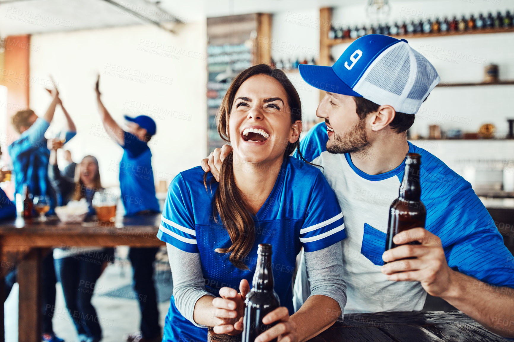 Buy stock photo Shot of a young couple having beer while watching the game in a bar