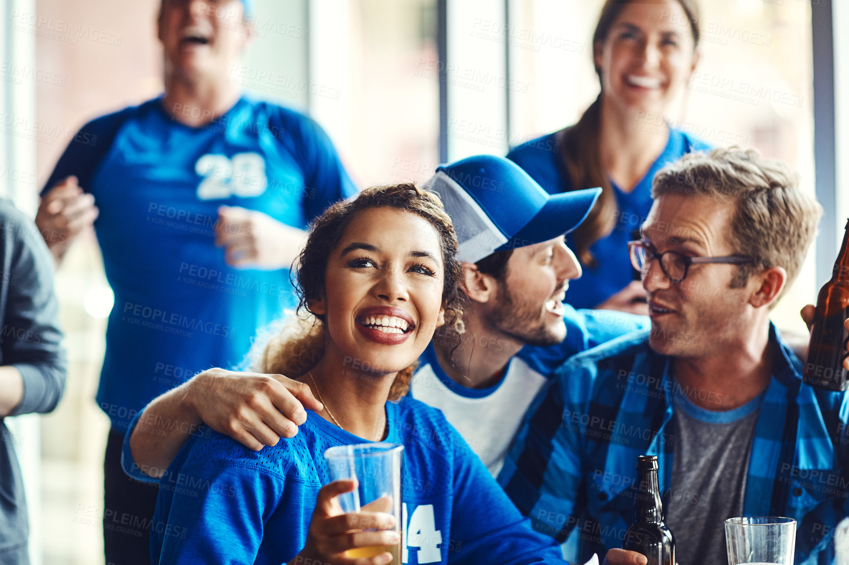 Buy stock photo A group of excited friends cheering on their favourite team at the bar