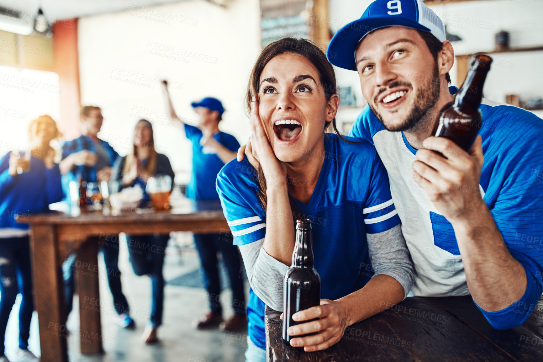 Buy stock photo Shot of a young couple having beer while watching the game in a bar