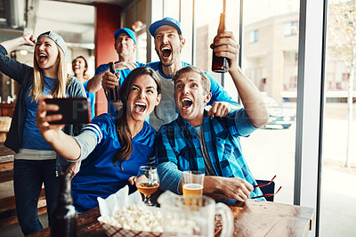 Buy stock photo Shot of a group of friends taking a selfie while watching a sports game at a bar