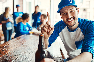 Buy stock photo Portrait of a man holding up one finger while watching a sports game with friends at a bar