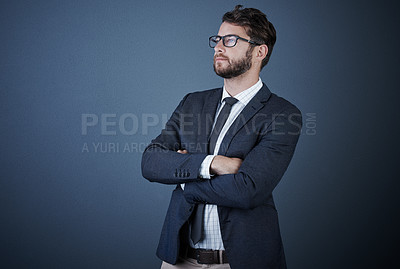 Buy stock photo Studio shot of a handsome young businessman standing with his arms crossed against a dark background