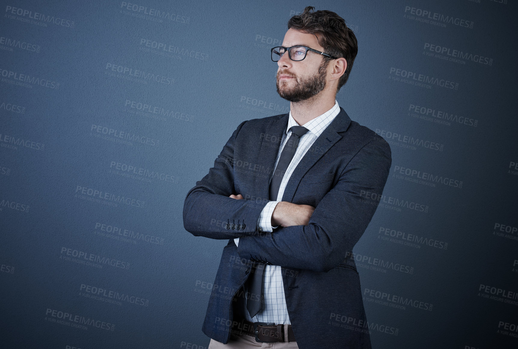 Buy stock photo Studio shot of a handsome young businessman standing with his arms crossed against a dark background