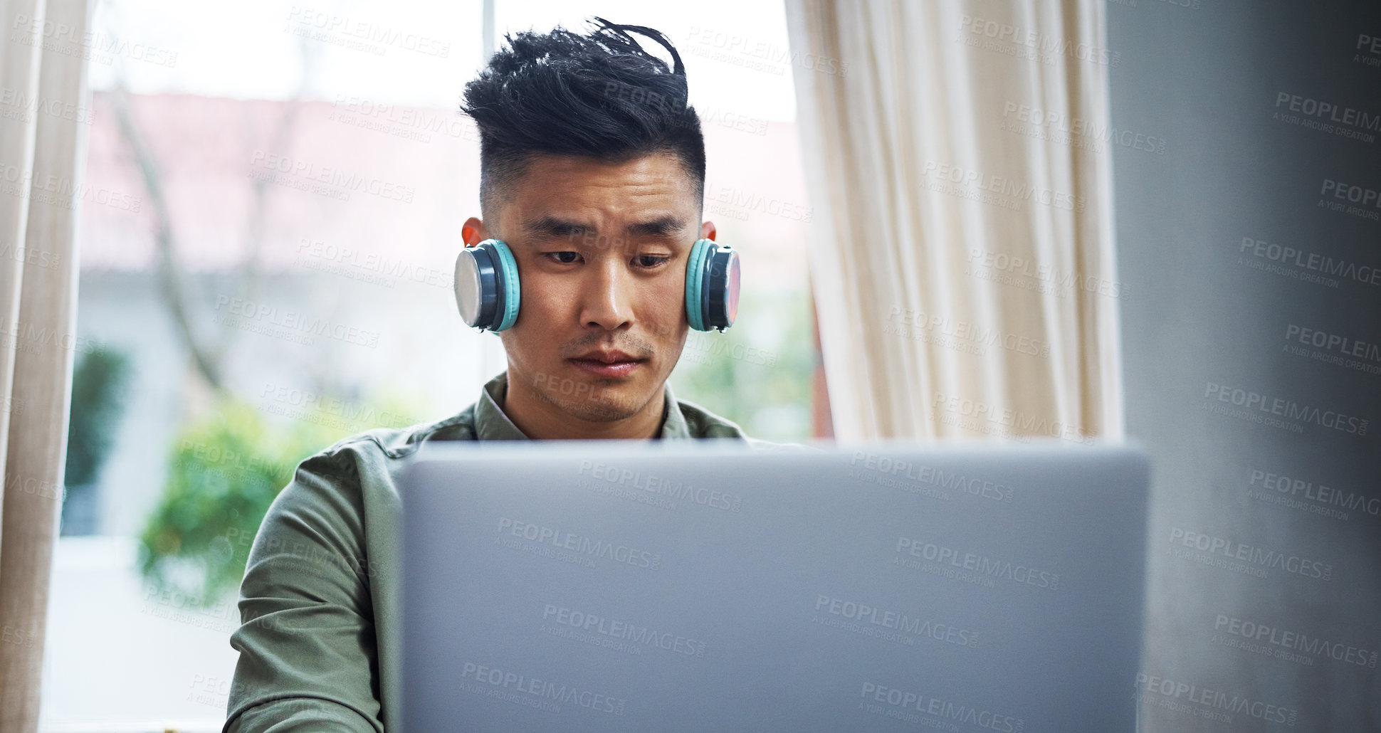 Buy stock photo Cropped shot of a handsome young man listening to music while working from home