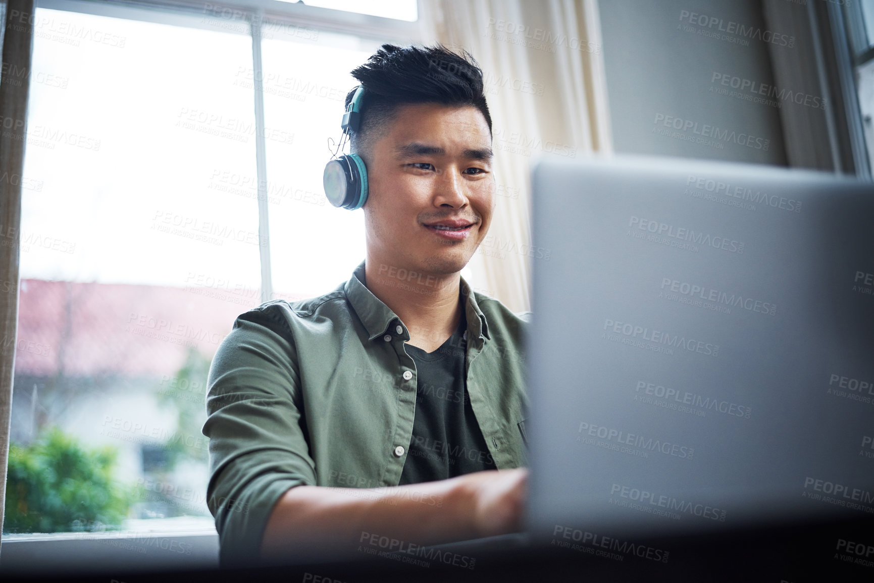 Buy stock photo Cropped shot of a handsome young man listening to music while working from home