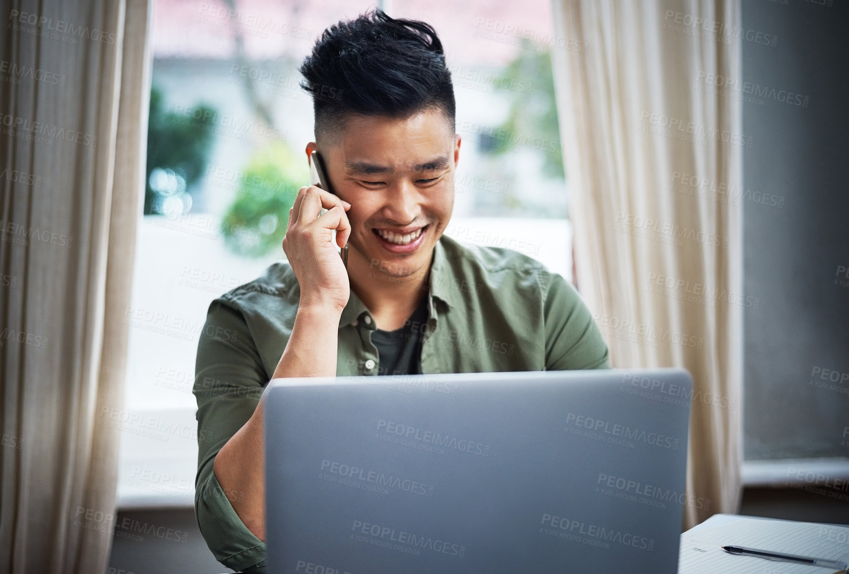 Buy stock photo Cropped shot of a handsome young man taking a call while working at home