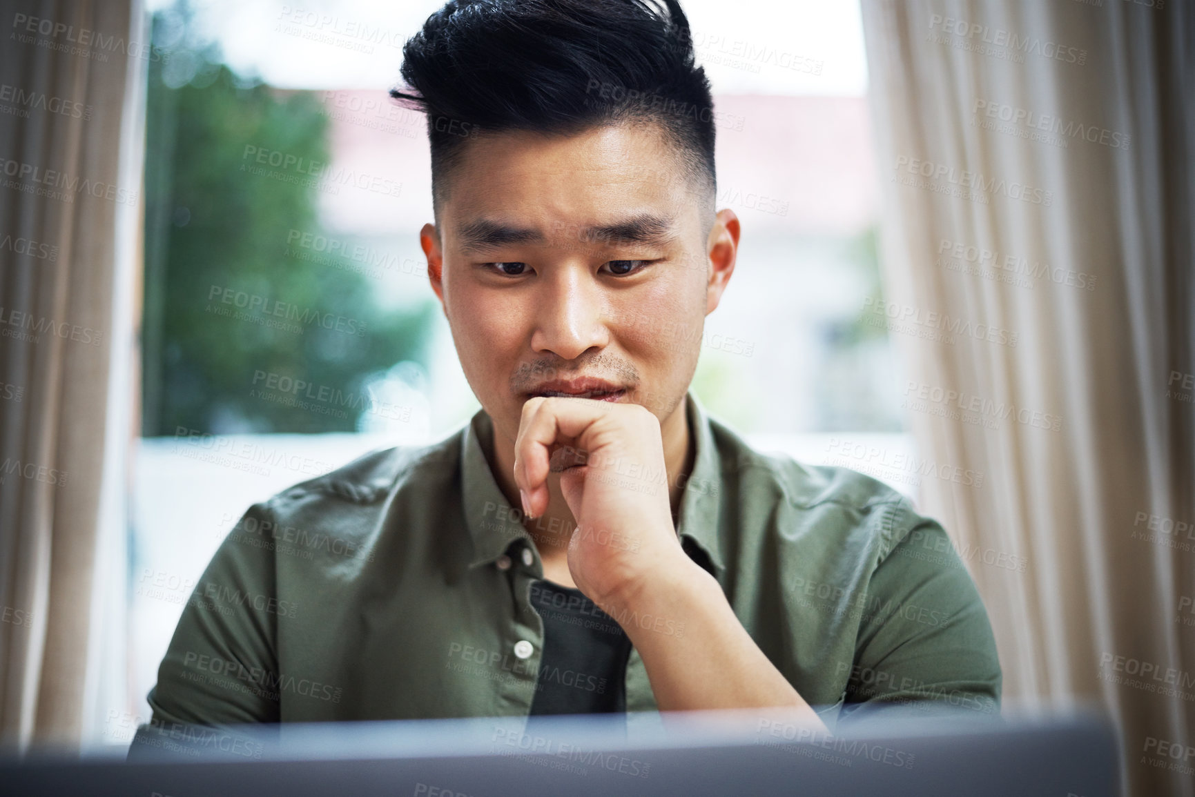 Buy stock photo Cropped shot of a handsome young man working on his laptop at home