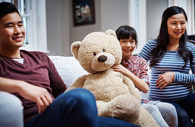 Buy stock photo Cropped portrait of a little girl sitting on the sofa with her teddybear between her parents