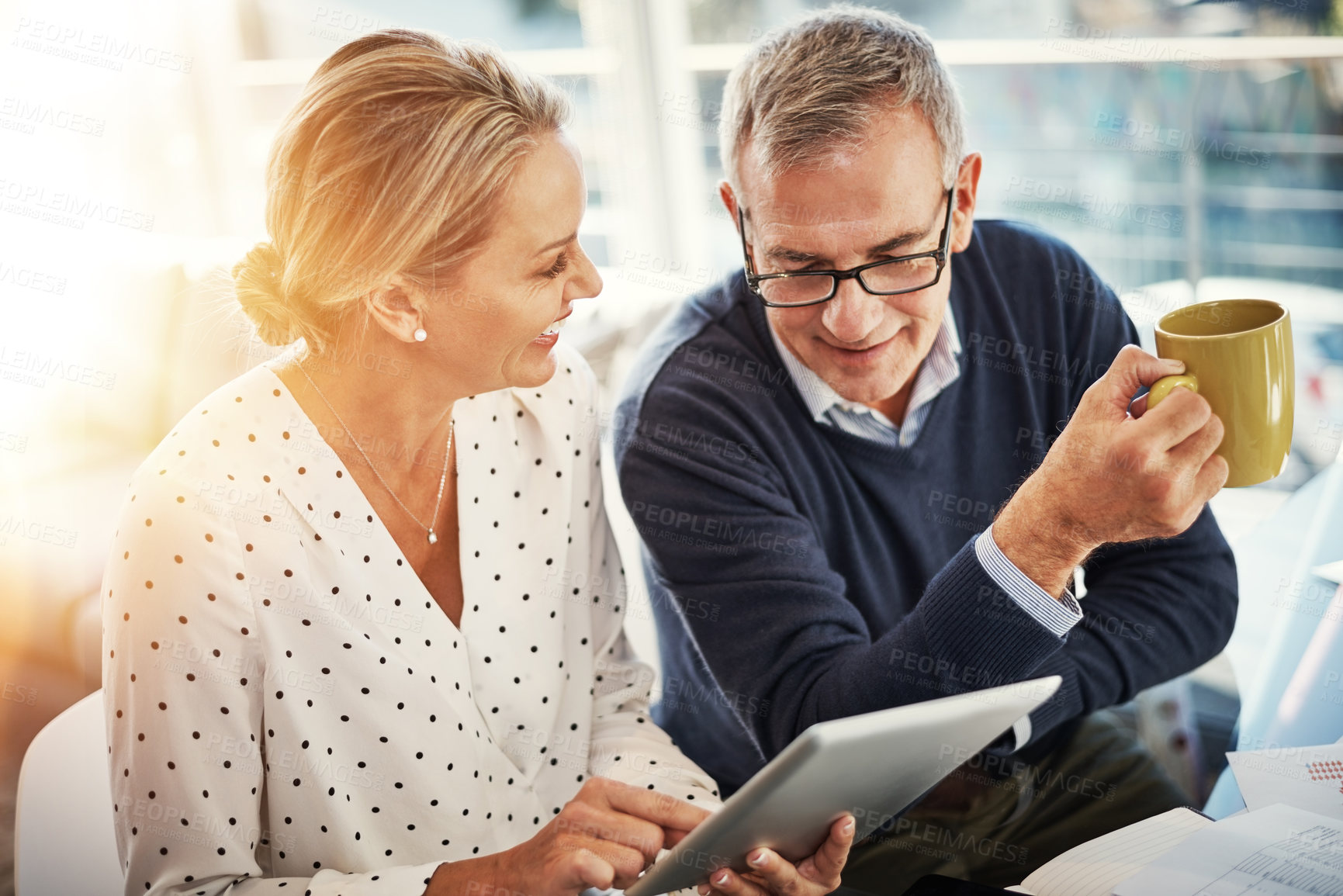 Buy stock photo Shot of a mature couple using a digital tablet while going through paperwork at home