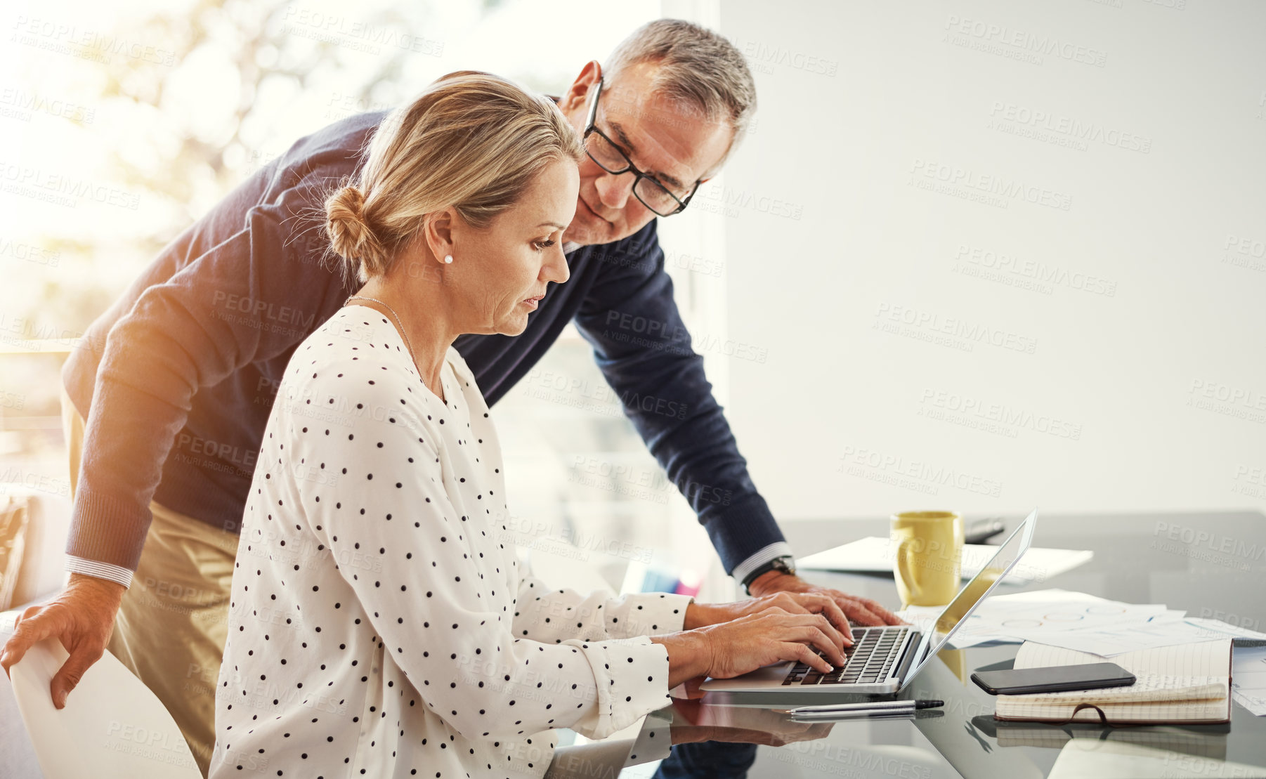 Buy stock photo Shot of a mature couple using a laptop while going through paperwork at home