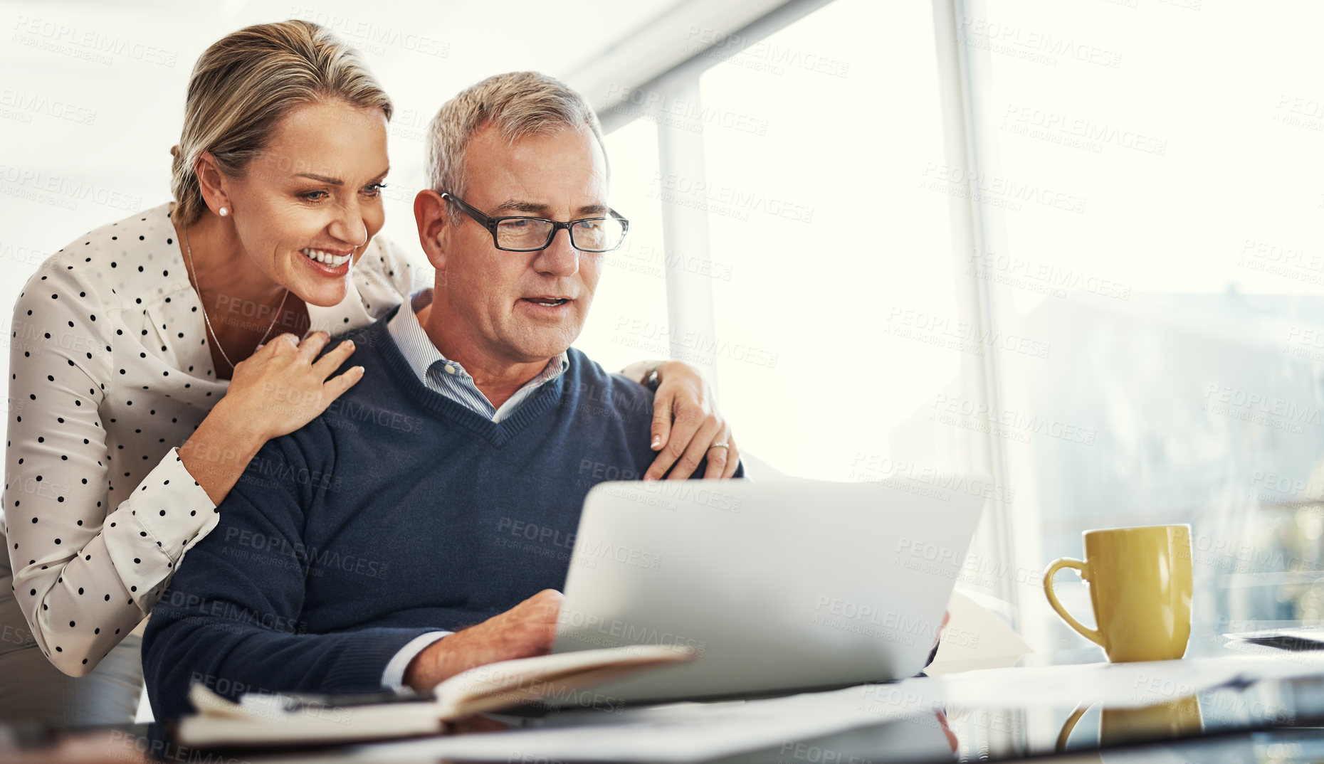 Buy stock photo Shot of a mature couple using a laptop while going through paperwork at home