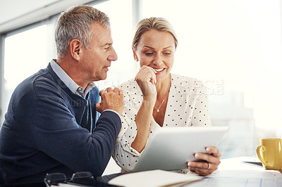 Buy stock photo Shot of a mature couple using a digital tablet while going through paperwork at home