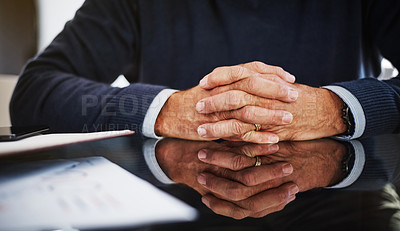 Buy stock photo Cropped shot of a businessman sitting at his work desk with his hands clasped