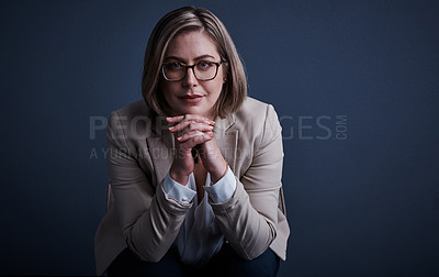 Buy stock photo Studio portrait of an attractive young corporate businesswoman posing against a dark background