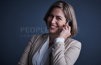 Buy stock photo Studio portrait of an attractive young corporate businesswoman making a call against a dark background