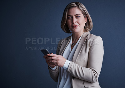 Buy stock photo Studio portrait of an attractive young corporate businesswoman sending a text against a dark background