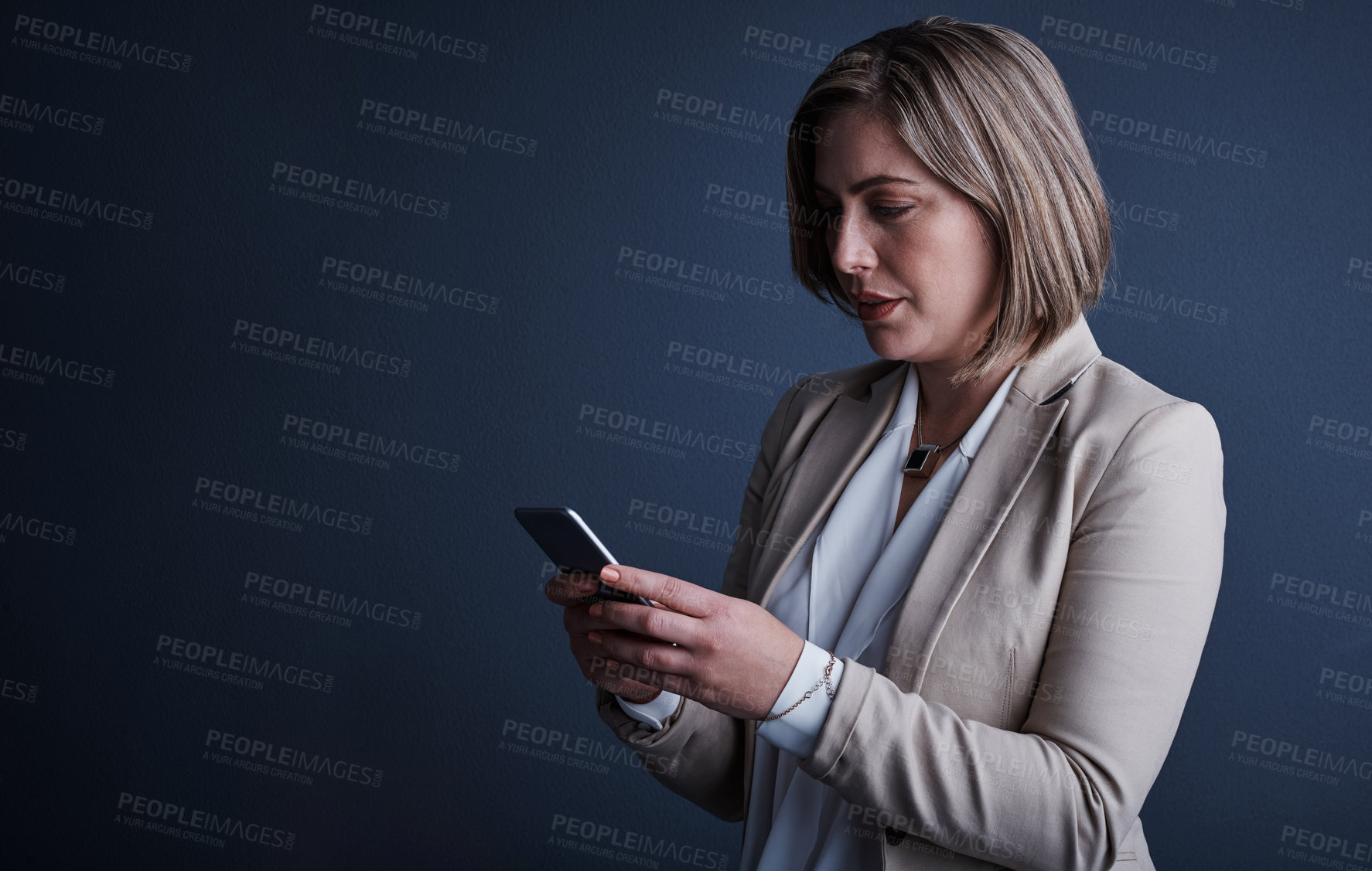 Buy stock photo Studio shot of an attractive young corporate businesswoman sending a text against a dark background