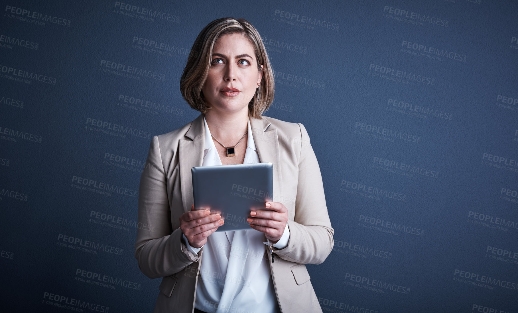 Buy stock photo Studio shot of an attractive young corporate businesswoman using a tablet against a dark background