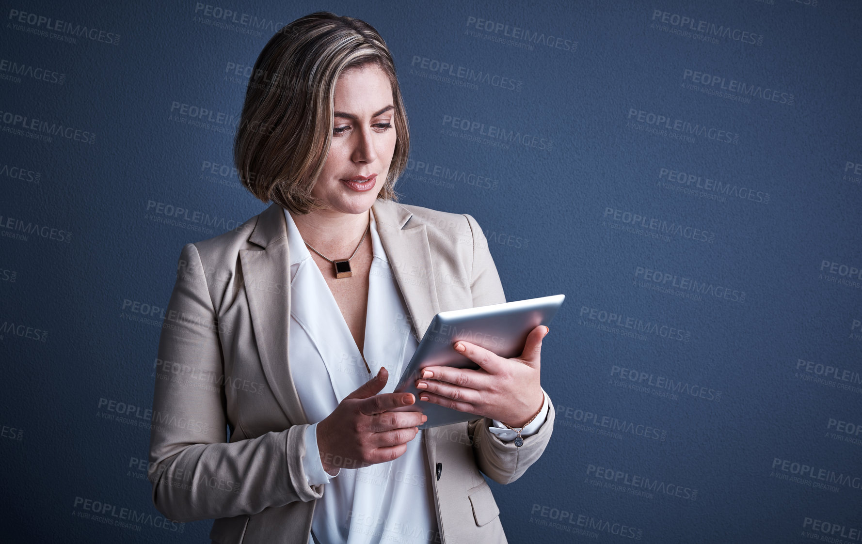 Buy stock photo Studio shot of an attractive young corporate businesswoman using a tablet against a dark background