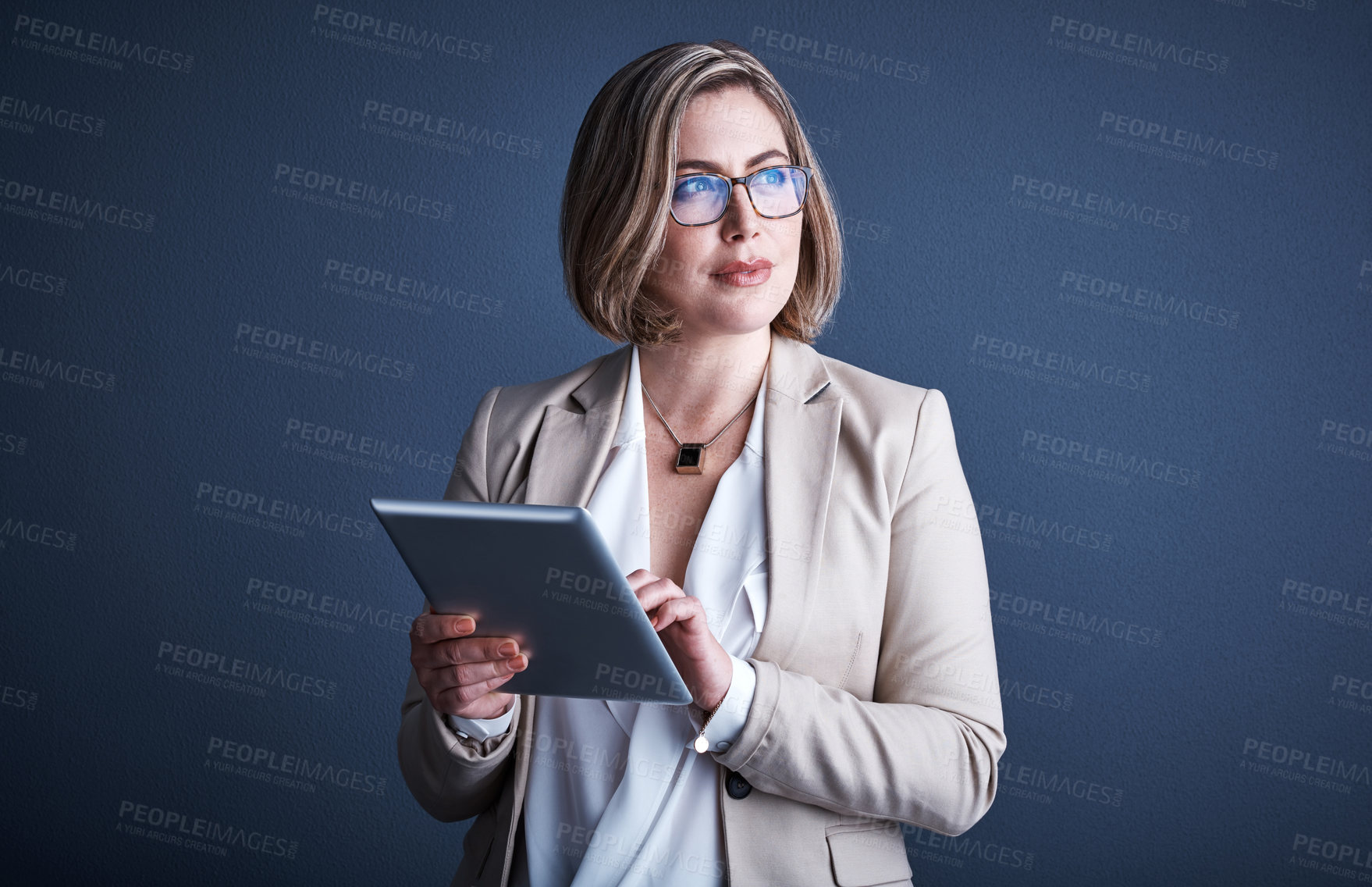 Buy stock photo Studio shot of an attractive young corporate businesswoman using a tablet against a dark background