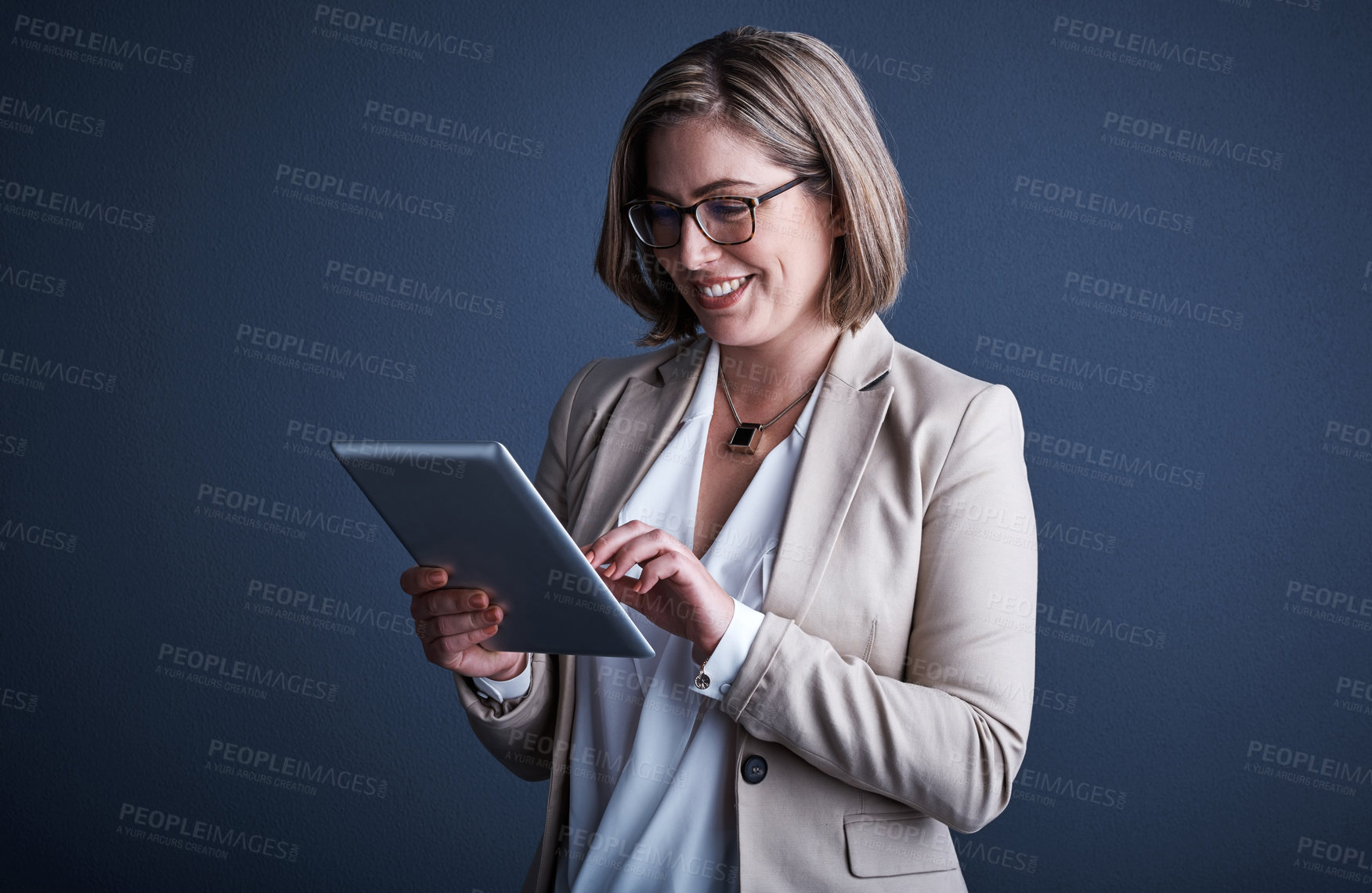 Buy stock photo Studio shot of an attractive young corporate businesswoman using a tablet against a dark background