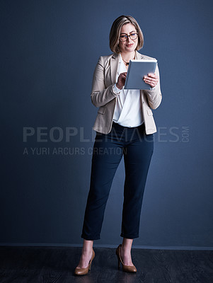 Buy stock photo Studio shot of an attractive young corporate businesswoman using a tablet against a dark background