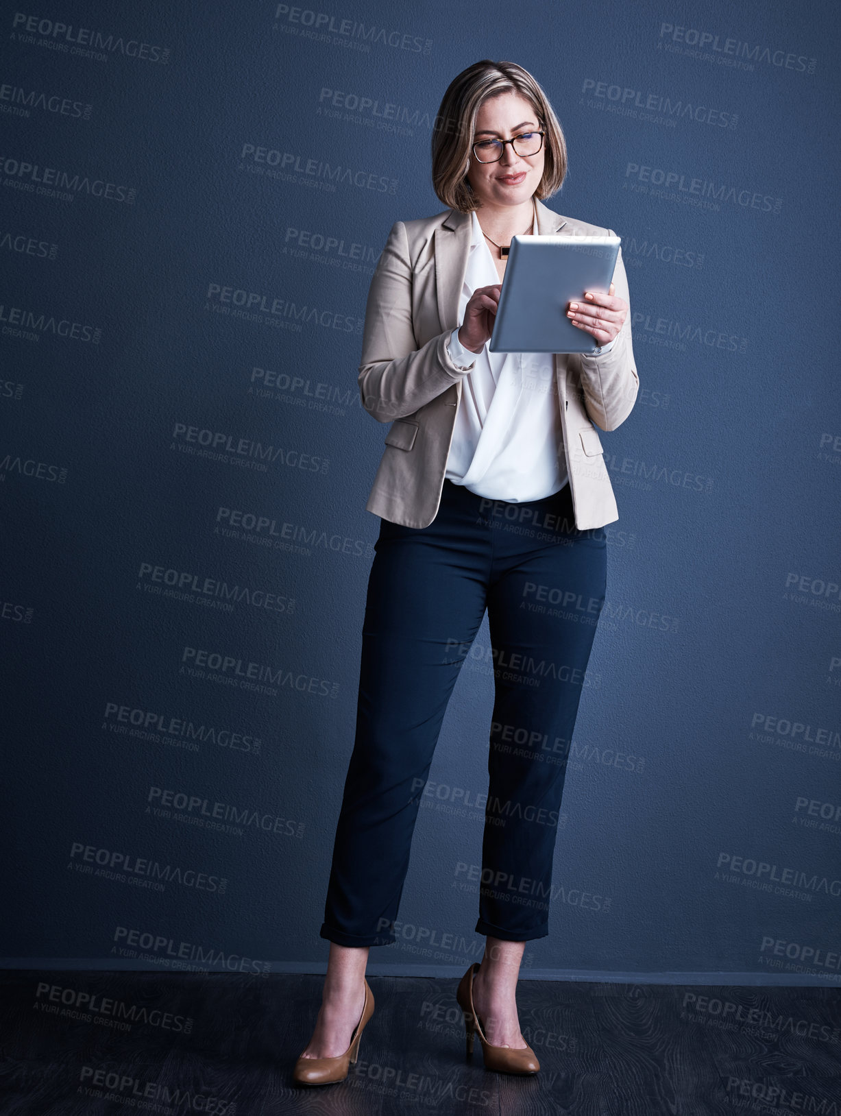 Buy stock photo Studio shot of an attractive young corporate businesswoman using a tablet against a dark background