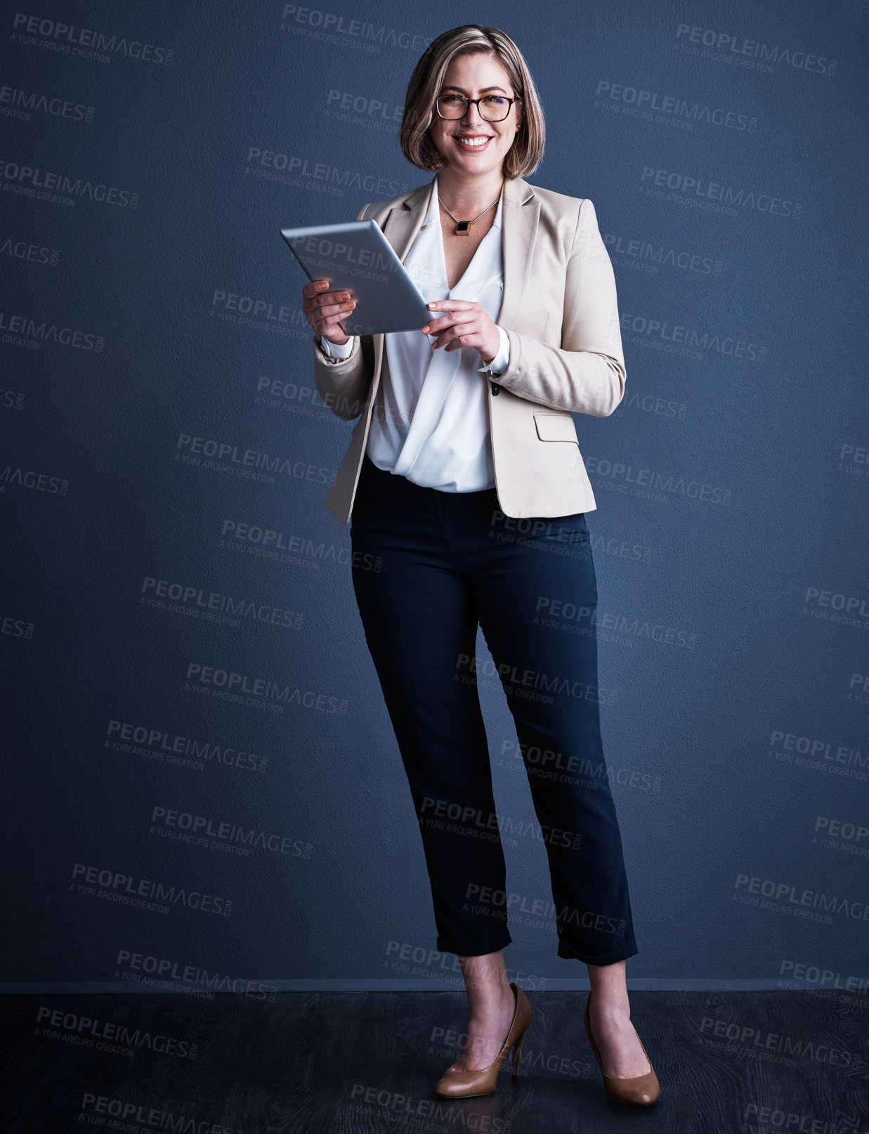 Buy stock photo Studio portrait of an attractive young corporate businesswoman using a tablet against a dark background