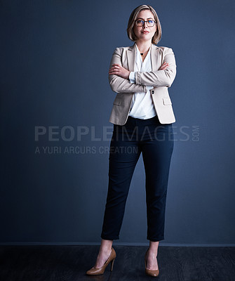 Buy stock photo Studio portrait of an attractive young corporate businesswoman posing with her arms crossed against a dark background