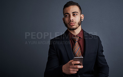 Buy stock photo Studio shot of a stylish young businessman looking thoughtful while sending a text message against a gray background