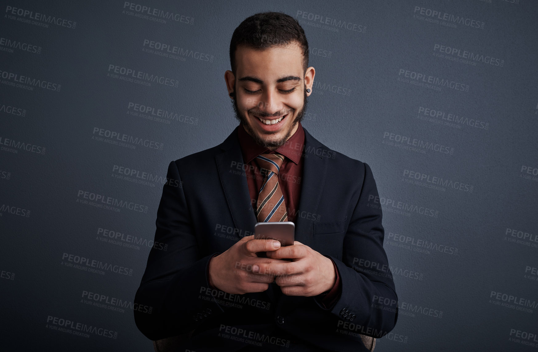 Buy stock photo Studio shot of a stylish young businessman sending a text message while standing against a gray background