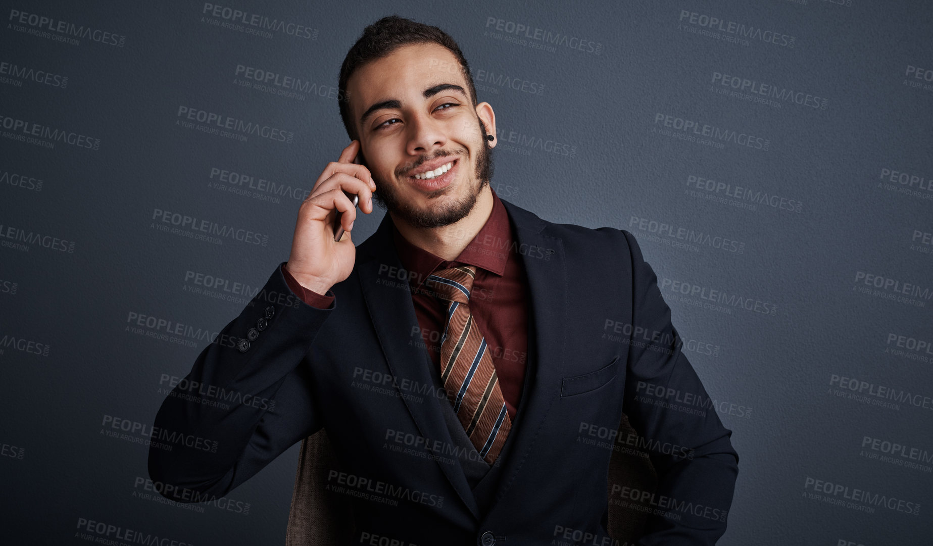 Buy stock photo Studio shot of a stylish young businessman looking thoughtful while making a phonecall against a gray background