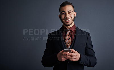 Buy stock photo Studio portrait of a stylish young businessman sending a text message while standing against a gray background