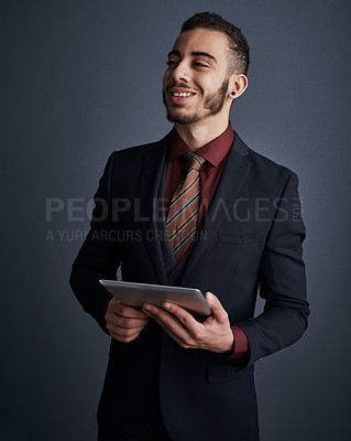 Buy stock photo Studio shot of a stylish young businessman looking thoughtful while using a tablet against a gray background