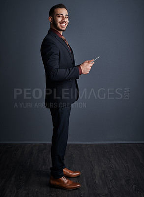 Buy stock photo Studio portrait of a stylish young businessman using a tablet against a gray background