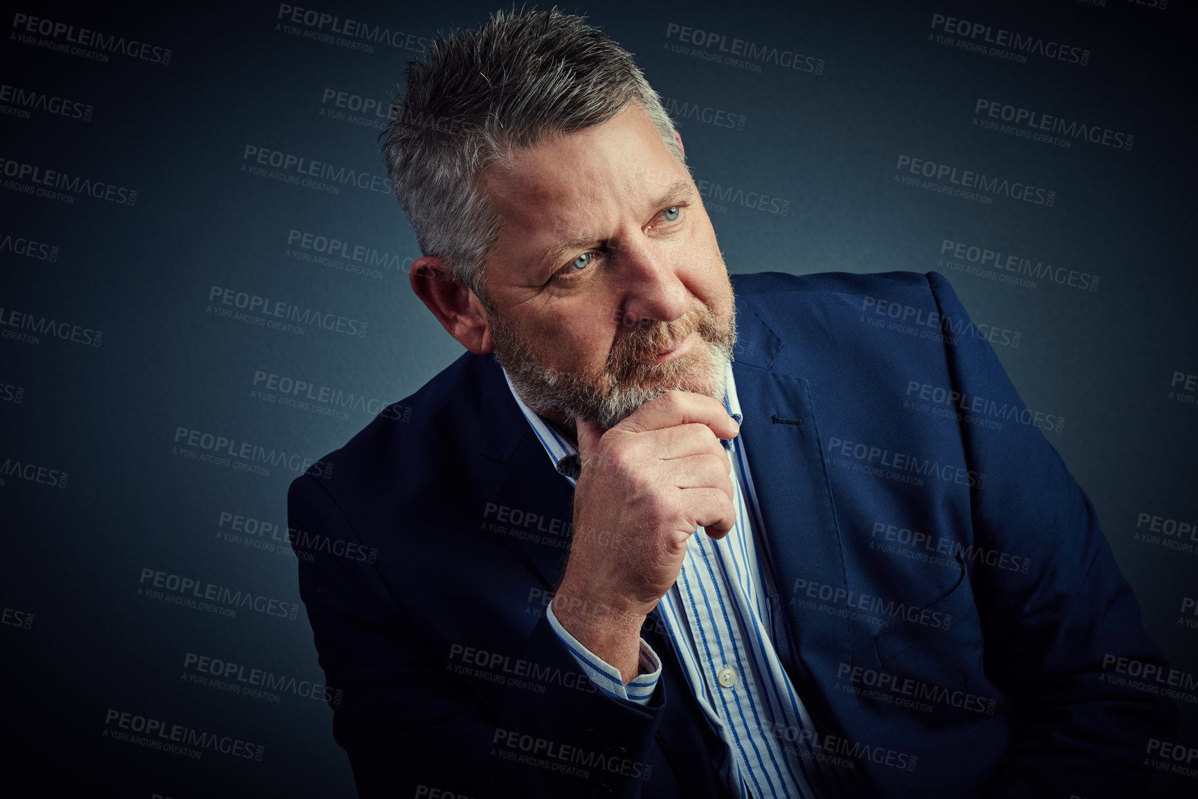 Buy stock photo Studio shot of a confident and mature businessman sitting with his hand on his chin against a dark background