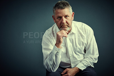 Buy stock photo Studio portrait of a handsome mature businessman looking thoughtful while sitting down against a dark background